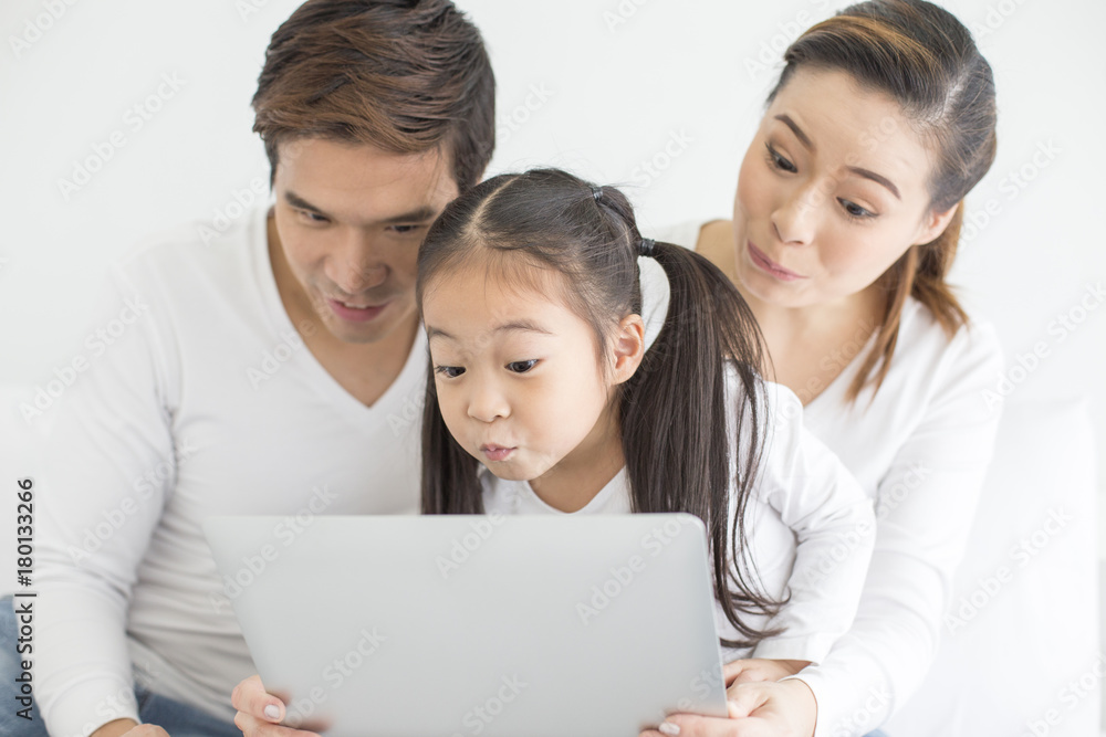 Attractive Little Girl using Laptop with Mom and Dad Together. Girl learning to use Laptop. Happy Family Concept. Attractive Little Girl using Laptop with Mom and Dad Together. Girl learning to use Laptop. Happy Family Concept.