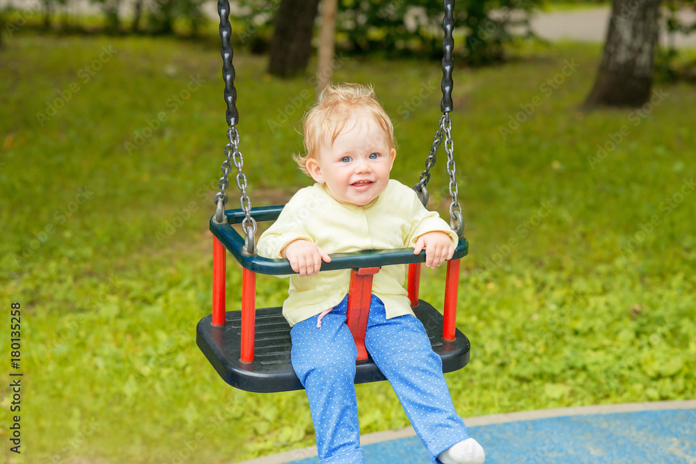 A cute baby child having fun on a swing