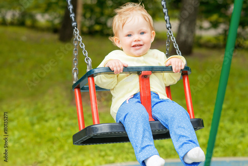 A cute baby child having fun on a swing