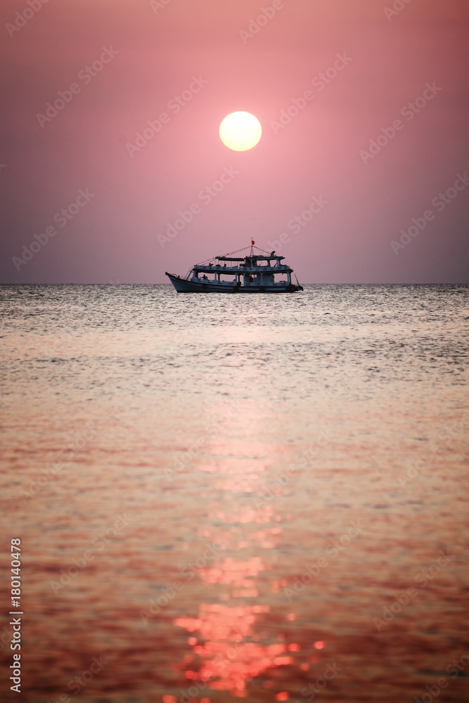 Sunset at the beach of Phu Quoc, sun disk beam and boat silhouette