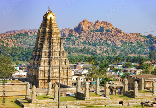 Virupaksha Temple, located in the ruins of ancient city Vijayanagar at Hampi, India. Landscape with unique mountain formation, tropical nature on the horizon and old hindu temple.