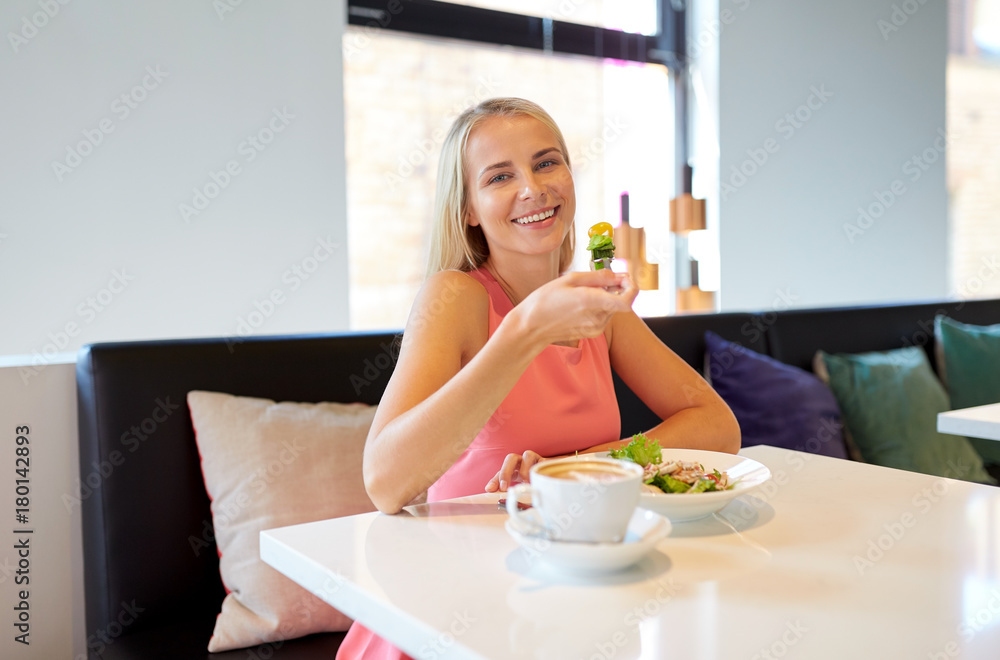 happy young woman eating lunch at restaurant