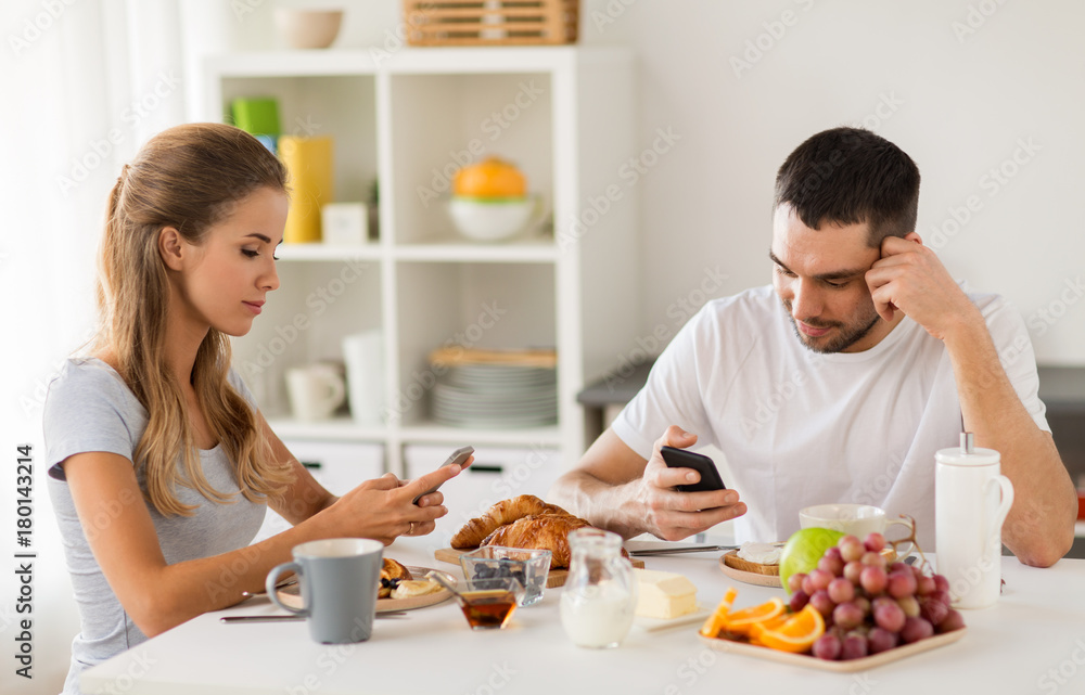 couple with smartphones having breakfast at home couple with smartphones having breakfast at home
