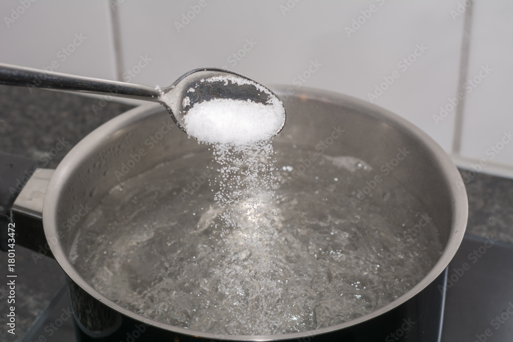 Salz in das kochende Wasser geben mit dem Löffel Salz in das kochende Wasser geben mit dem Löffel