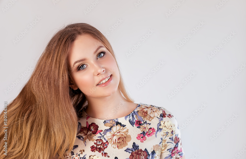 Close-up portrait of a smiling beautiful blonde caucasian woman with blue eyes, looking at camera, on a gray background with copy-space Close-up portrait of a smiling beautiful blonde caucasian woman with blue eyes, looking at camera, on a gray background with copy-space