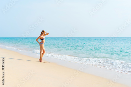 Beautiful and sexy girl in swimsuit posing on a beach at summer. Sea and sky background.