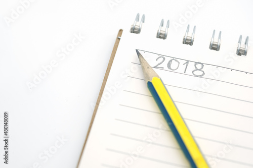 New year Planning concept. Close up of notebook with number 2018 hand writing and pencil on white background.