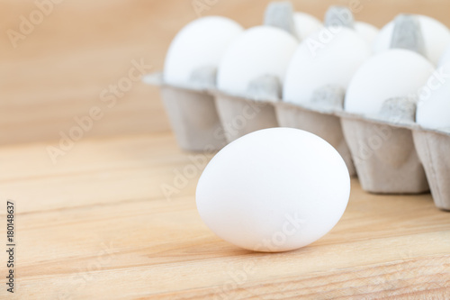 Close-up of raw chicken eggs in egg box on wooden background