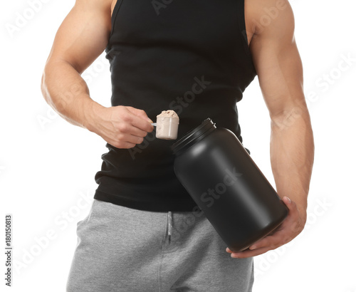 Sporty young man with jar and scoop of protein powder on white background photo