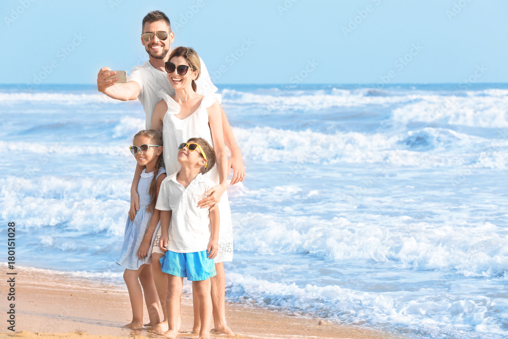 Happy family taking selfie on sea beach at resort
