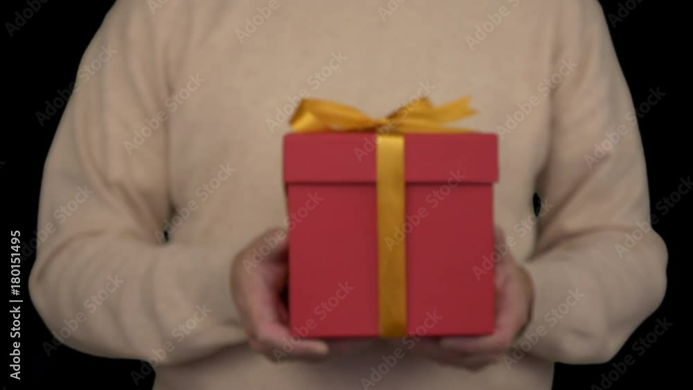 Caucasian man in beige sweater is holding a gift box in hands. Front view of man in casual beige sweater. Man gives a gift. Alpha channel chroma key transparent background. Locked down. From unfocus. Caucasian man in beige sweater is holding a gift box in hands. Front view of man in casual beige sweater. Man gives a gift. Alpha channel chroma key transparent background. Locked down. From unfocus.