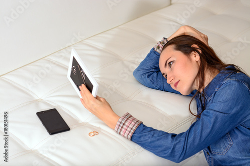 Εκτύπωση καμβά Sad woman after the divorce, looking at a family photo in the frame sitting on the floor near the sofa in the room