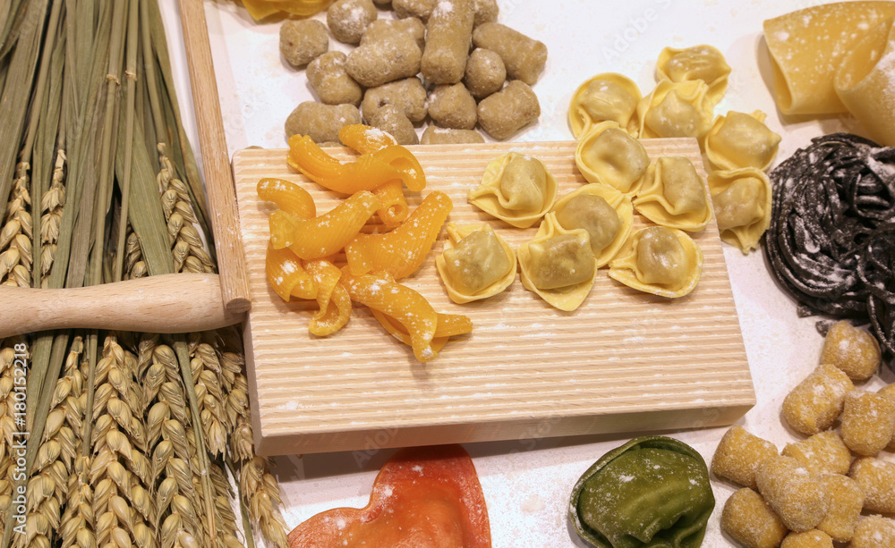 Fototapeta premium cutting board with ravioli and fresh pasta with black cuttlefish