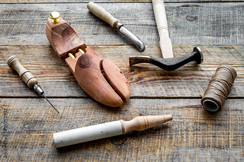 Tools for repair shoes. Wooden last, hammer, awl, knife, thread on wooden background