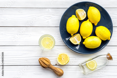 Make lemonade at home. Lemons, juicer, glass and bottle for beverage on white wooden background top view copyspace