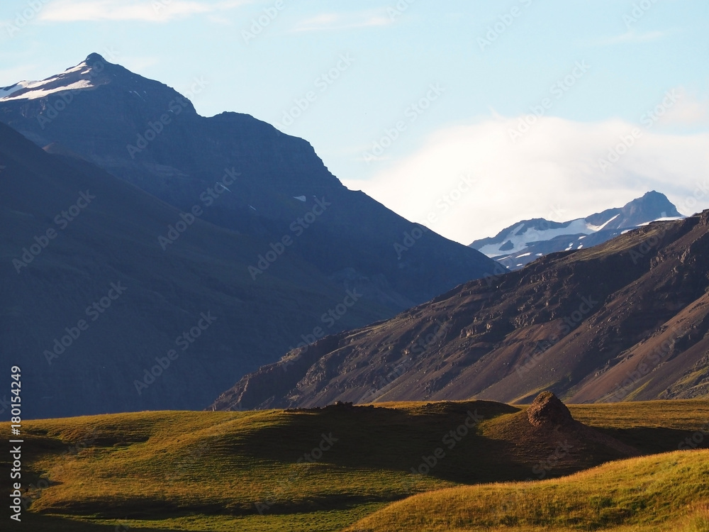 view on snow covered mountains and green grass hills in evening light Iceland nature
