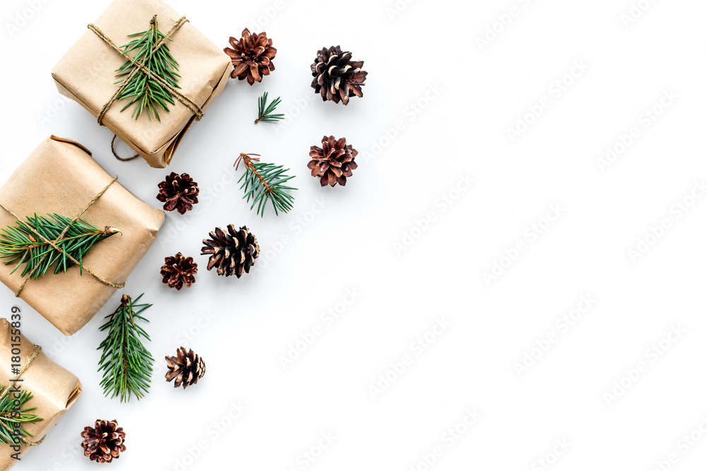 Gifts for new year wrapped in craft paper near spruce branches and cones on white background top view copyspace Gifts for new year wrapped in craft paper near spruce branches and cones on white background top view copyspace