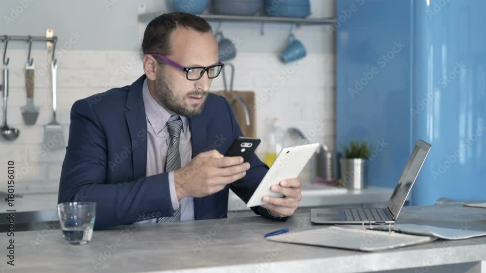 Businessman working with tablet computer, smartphone in kitchen at home
Businessman working with tablet computer, smartphone in kitchen at home