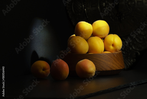 Yellow apricots on a black background in a beam of the sun