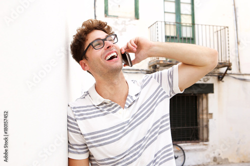 Laughing man talking on smart phone on city street