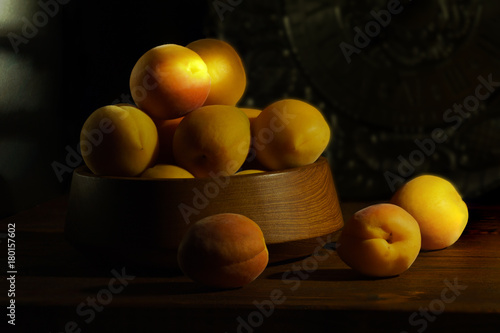 Yellow apricots on a black background in a beam of the sun