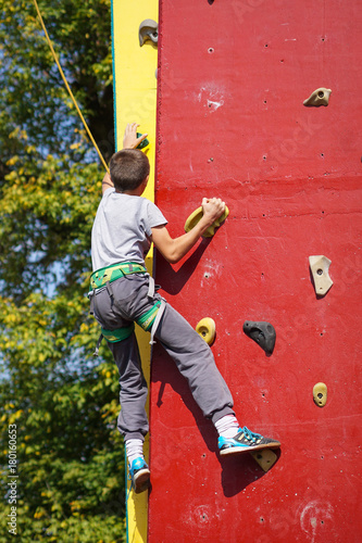 Young boy climbs on artificial climbing wall