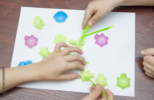 дети лепят из пластилина разные фигурки на белом листе бумаги