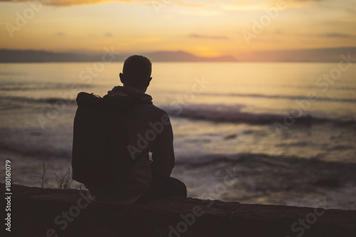 Hipster hiker tourist with backpack looking of seascape sunset on background blue sea, enjoying ocean horizon, panoramic sunrise, traveler relax holiday concept, sunlight view in trip vacation