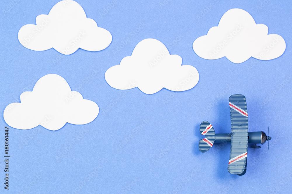 toy airplane on a background of blue sky with paper clouds. The concept