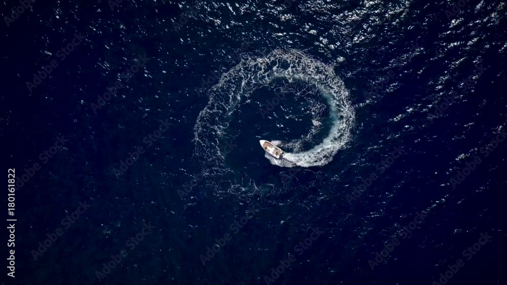 Aerial view of a motor boat designing a circle in the sea navigating fast Aerial view of a motor boat designing a circle in the sea navigating fast