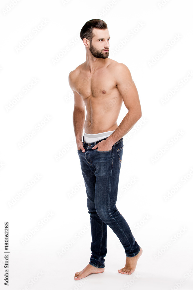 Pure masculinity. Full length of handsome young man in jeans looking away while standing against white background. Pure masculinity. Full length of handsome young man in jeans looking away while standing against white background.