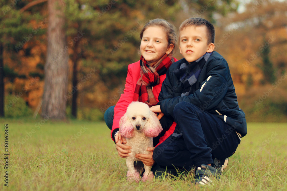 A boy with a girl is played with a dog in the park A boy with a girl is played with a dog in the park