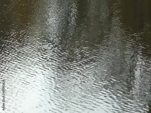 The ripples on the lake are changing the reflection on the surface of the water.