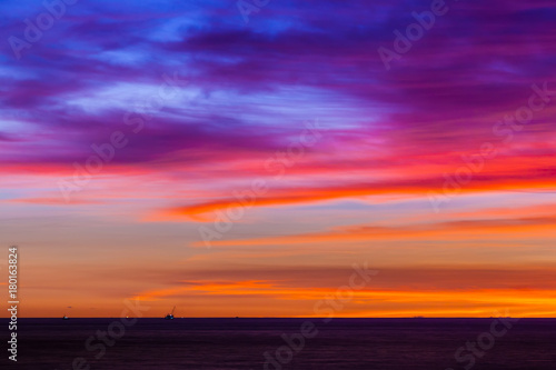 Stunning colorful sunset, blue sky, yellow purple cirrus clouds, orange sun, dark sea. Sunset on Jimbaran, South Kuta, Bali, Indonesia. © Valery Bocman