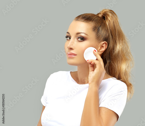 Beauty care woman using cotton pad , isolated on grey background. Skin care and beauty concept.