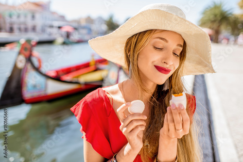 Young woman tourist holding portuguese delicacy called Ovos Moles made of egg yolks and sugar on the water channal background in Aveiro city, Portugal photo