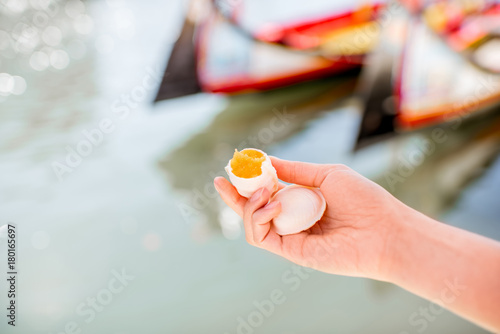 Holding portuguese delicacy called Ovos Moles made of egg yolks and sugar on the water channal background in Aveiro city, Portugal