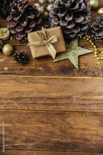 Christmas background with pine cones and gift box on wooden table.