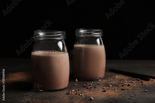 Glass jars with delicious cocoa drink on table