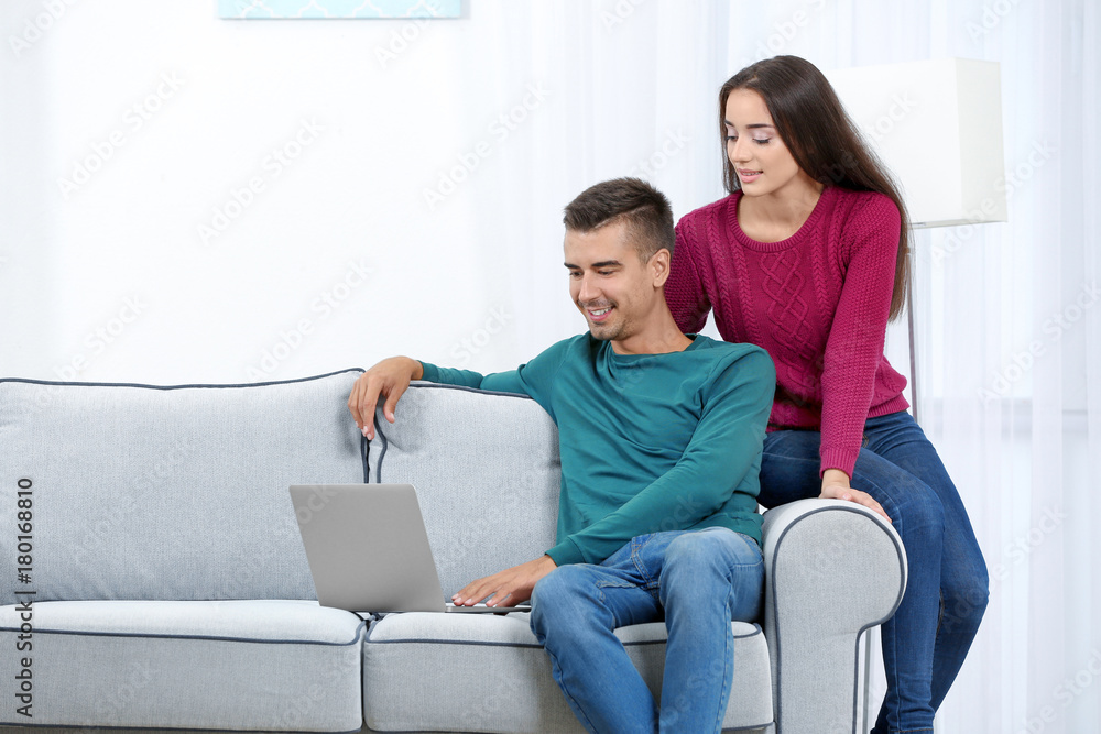 Young couple with laptop on sofa at home Young couple with laptop on sofa at home