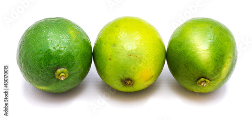 Three whole green limes in row isolated on white background.