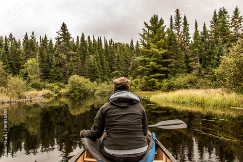 Girl canoeing with Canoe on the lake of two rivers in the algonquin national park in Ontario Canada on cloudy day © CL-Medien