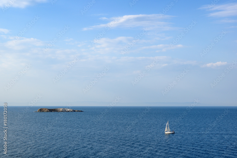 Seascape with sailing yacht and small island in sea