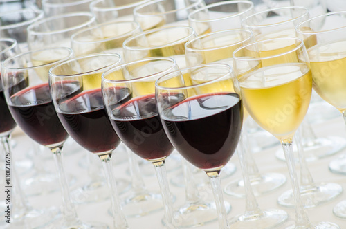 rows of wine glasses with red and white wine on a buffet table