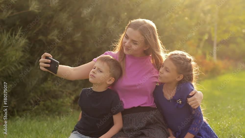 Young mother with children making selfie on smartphone. They have fun taking photos for a family album Young mother with children making selfie on smartphone. They have fun taking photos for a family album