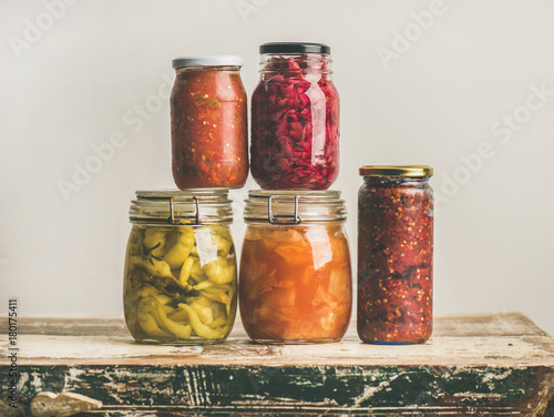 Εκτύπωση καμβά Autumn seasonal pickled or fermented colorful vegetables in glass jars over vintage kitchen drawer, white wall background, copy space