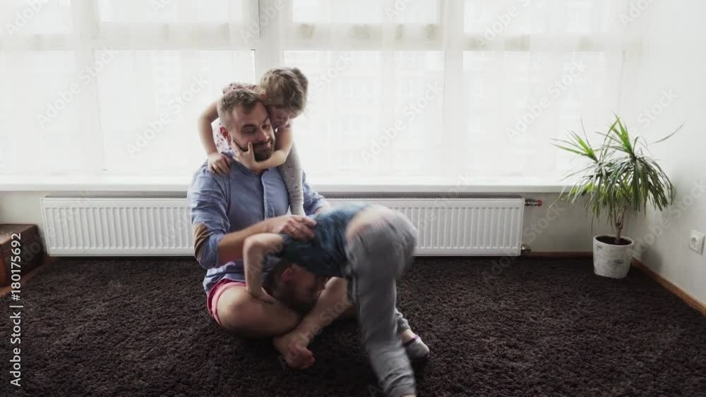 Happy children playing with his father on the floor
