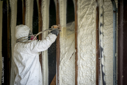 Worker spraying closed cell spray foam insulation on a home that was flooded by Hurricane Harvey photo