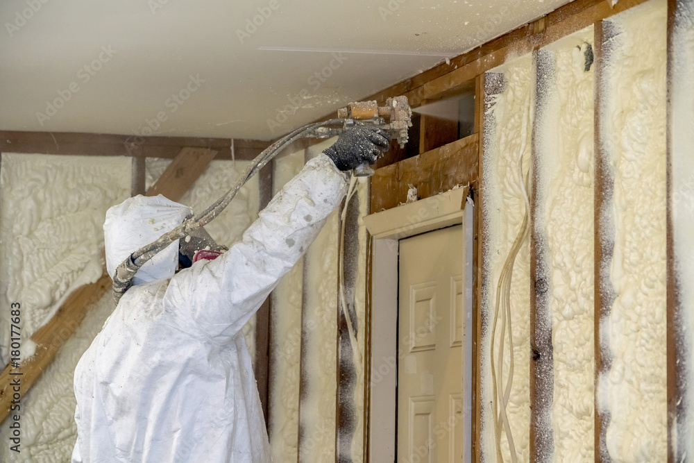 Worker spraying closed cell spray foam insulation on a home that was  flooded by Hurricane Harvey Photos | Adobe Stock