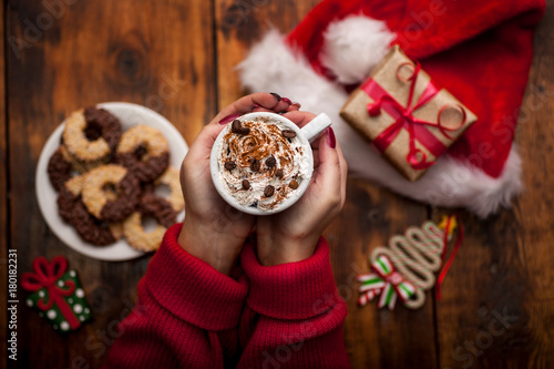 Hands holding coffee cup on Christmas decorations background.